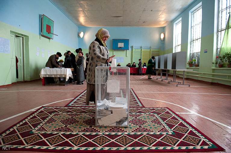 A person casting a ballot in a gymnasium.
